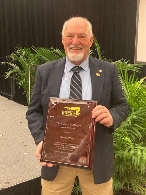 Jim Meier holding his award plaque at the 2023 Torch Run Hall of Fame event