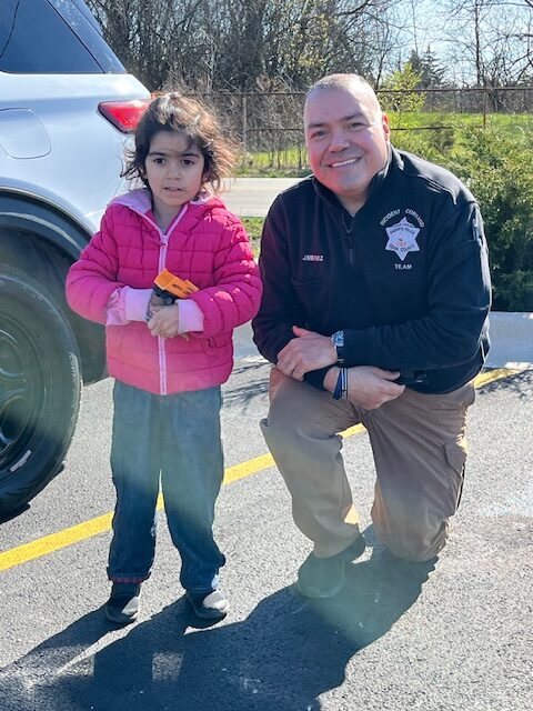 Member of the Sheriff's office standing near a young child at the Touch a Truck event in Maine Township