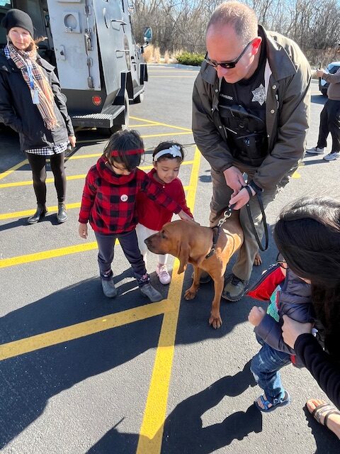 Member of the Sheriff's Office allowing children to pet a K9 at the Touch a Truck event in Maine Township