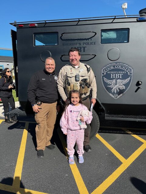 Members of the Sheriff's Office standing with a young child at the Touch a Truck event in Maine Township