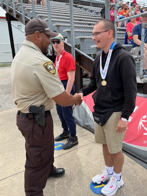 Special Olympics Ceremony participant shaking hands with member of Sheriff's Office