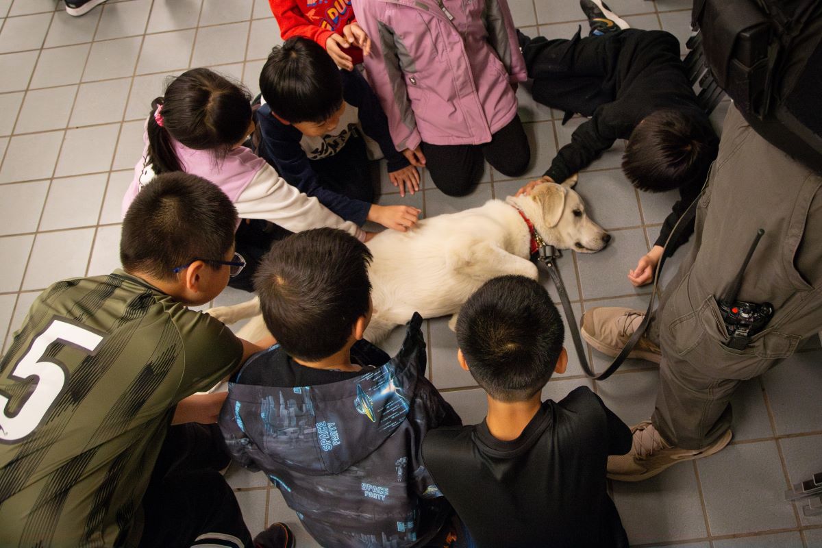 Young individuals petting a K9 at the Haines Game Night
