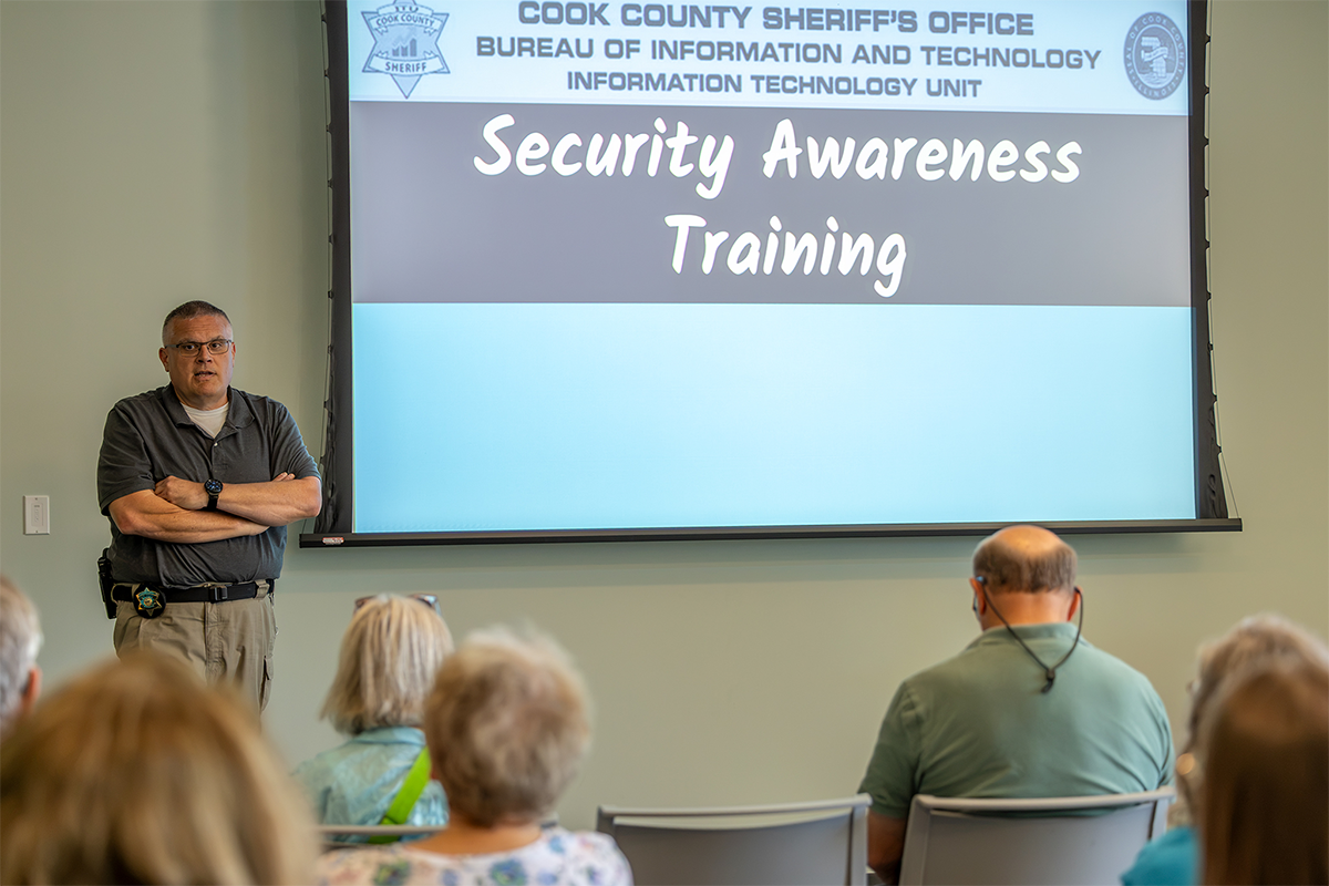 A presenter stands before an audience during a Security Awareness Training session hosted by the Cook County Sheriff's Office.